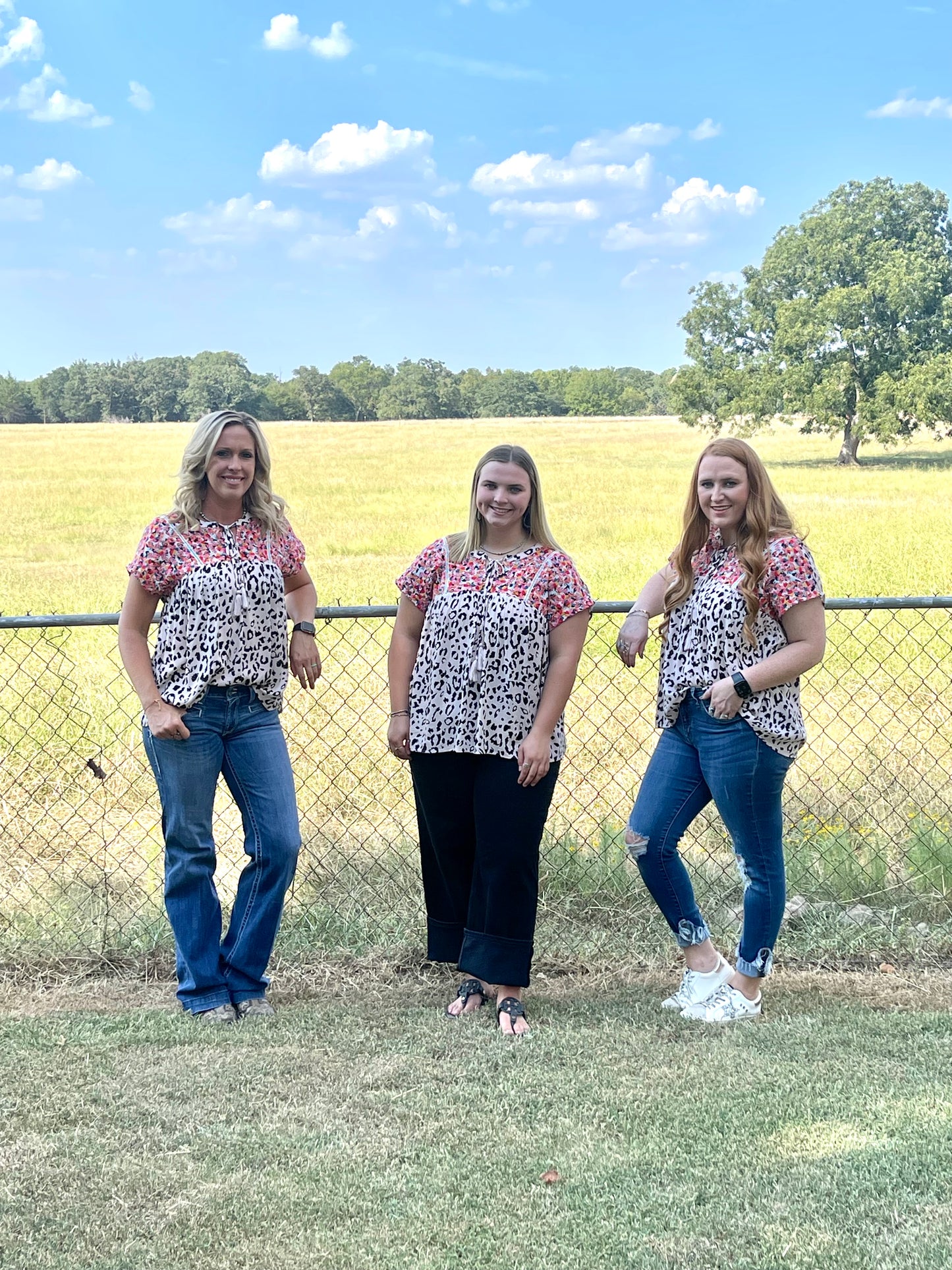 Three women wearing black and white cheetah blouse with colorful embroidery and tassel tie in different sizes