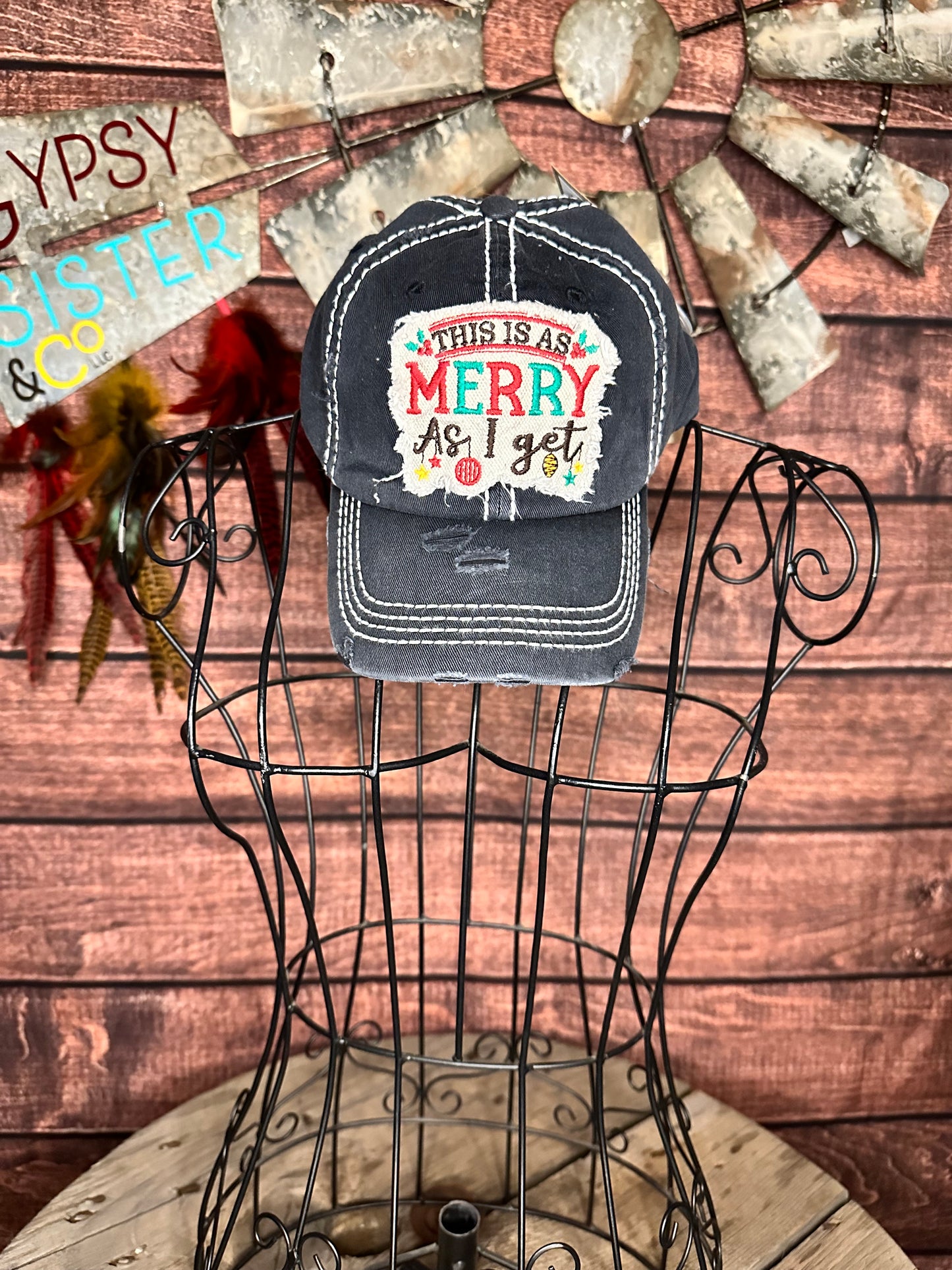 Black distressed ball cap with distressed white patch that says "This is as Merry as I get"