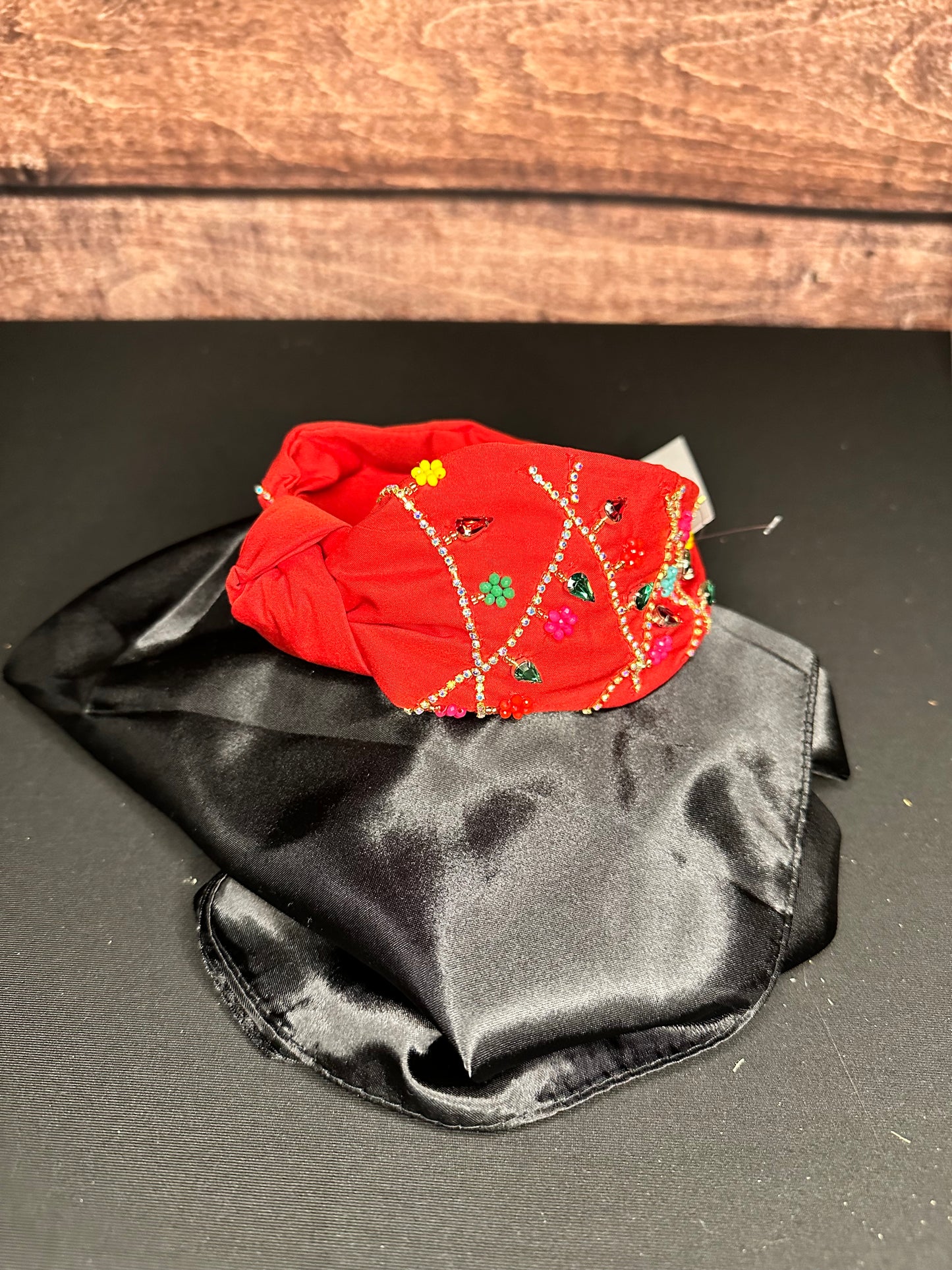 Red knotted headband with gold and colorful beading that resembles strings of ornaments