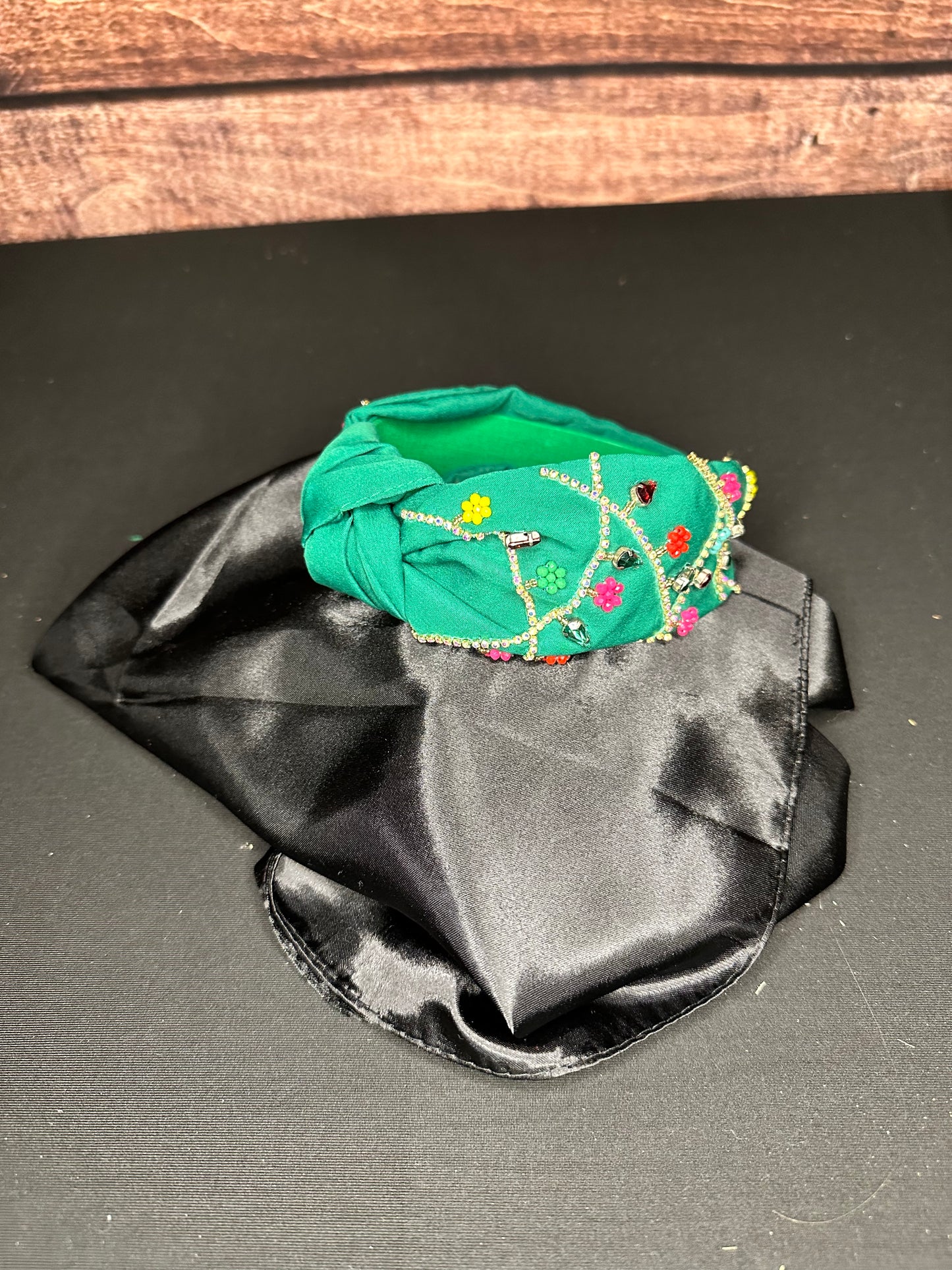 Green knotted headband with gold and colorful beading that resembles ornament strings