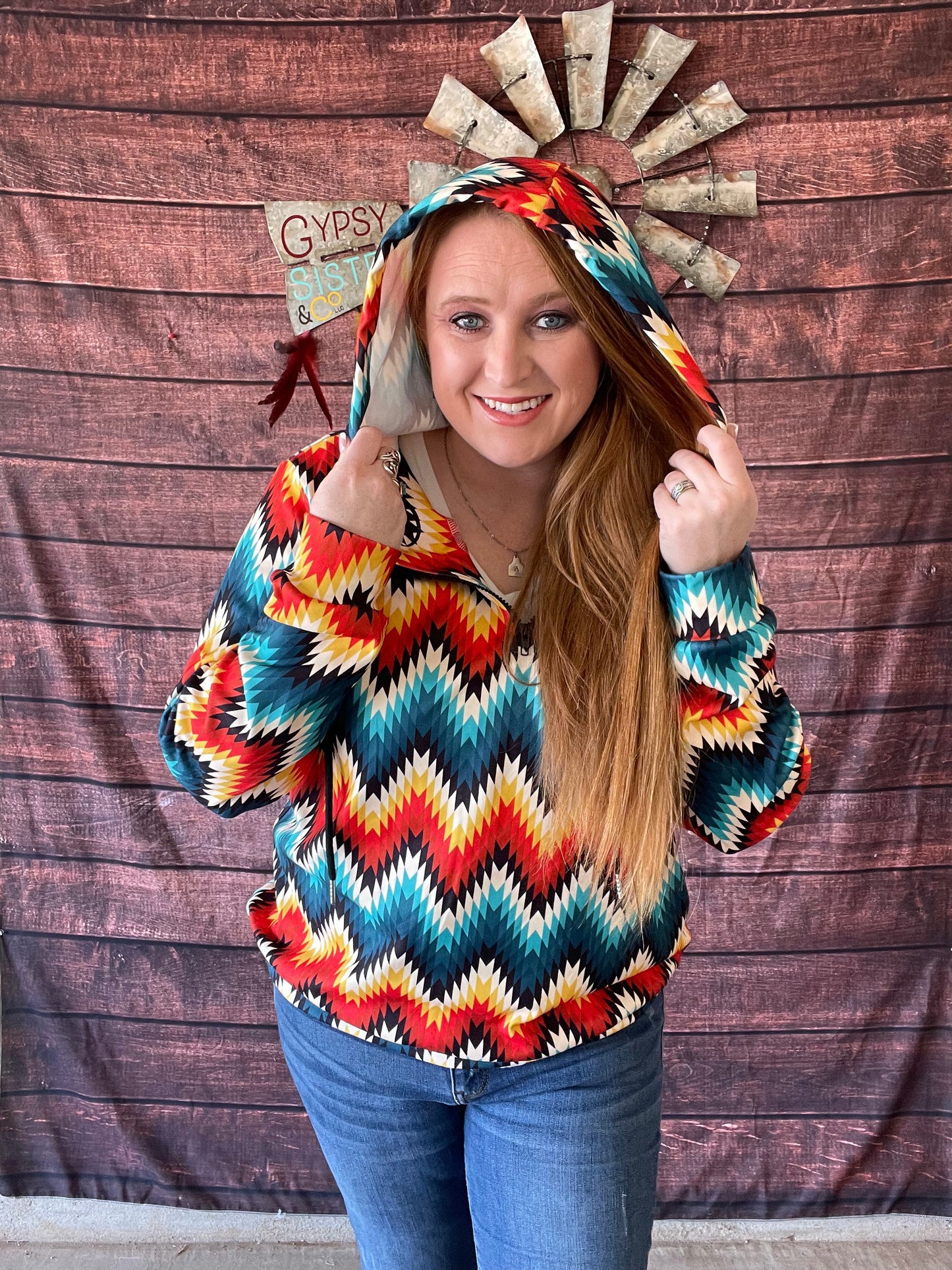 Model wearing bright colored Aztec print quarter zip hoodie in size large with hood up on head