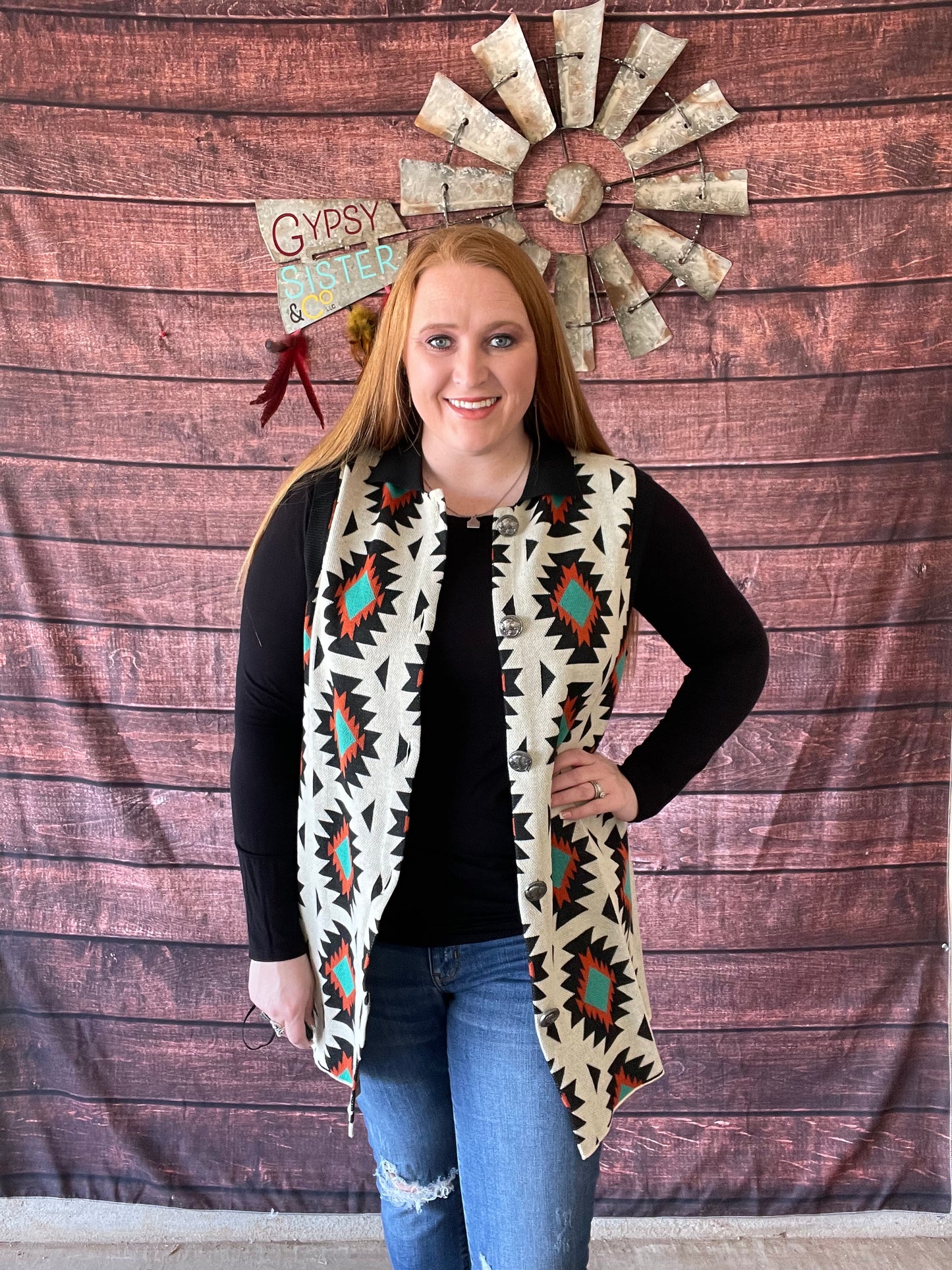 Model wearing cream sweater vest with rust and turquoise Aztec detailing along with black collar and buffalo nickel buttons in size large
