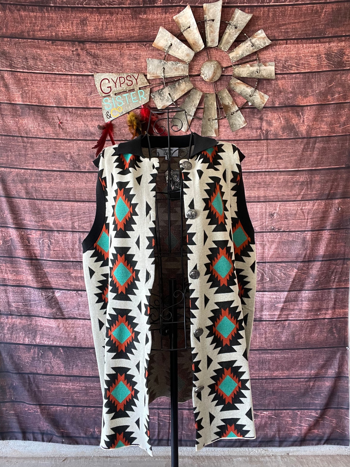Cream sweater vest with rust and turquoise Aztec detailing along with black collar and buffalo nickel buttons