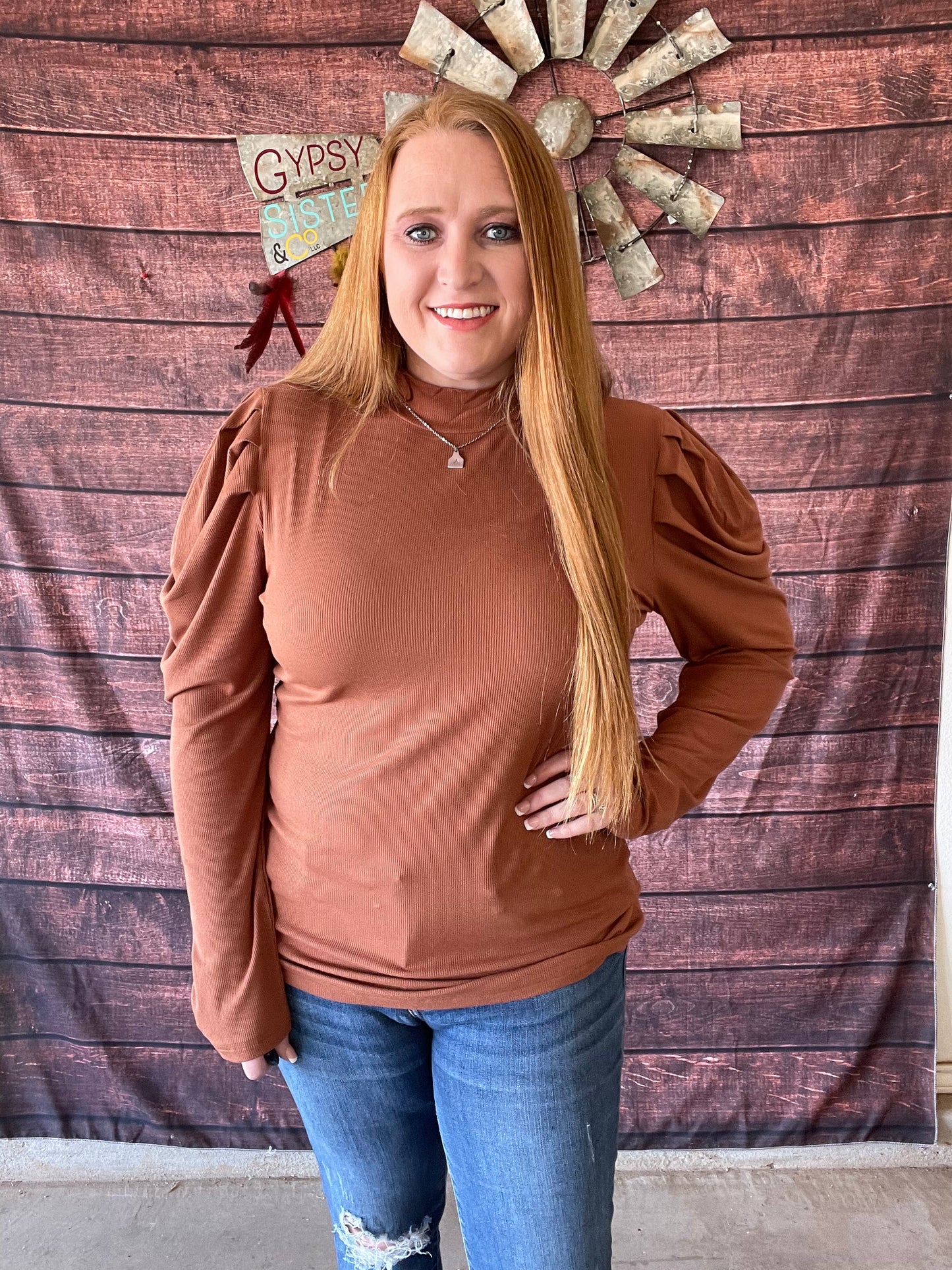 Model wearing brown top with mock neck and puffy sleeves in size large