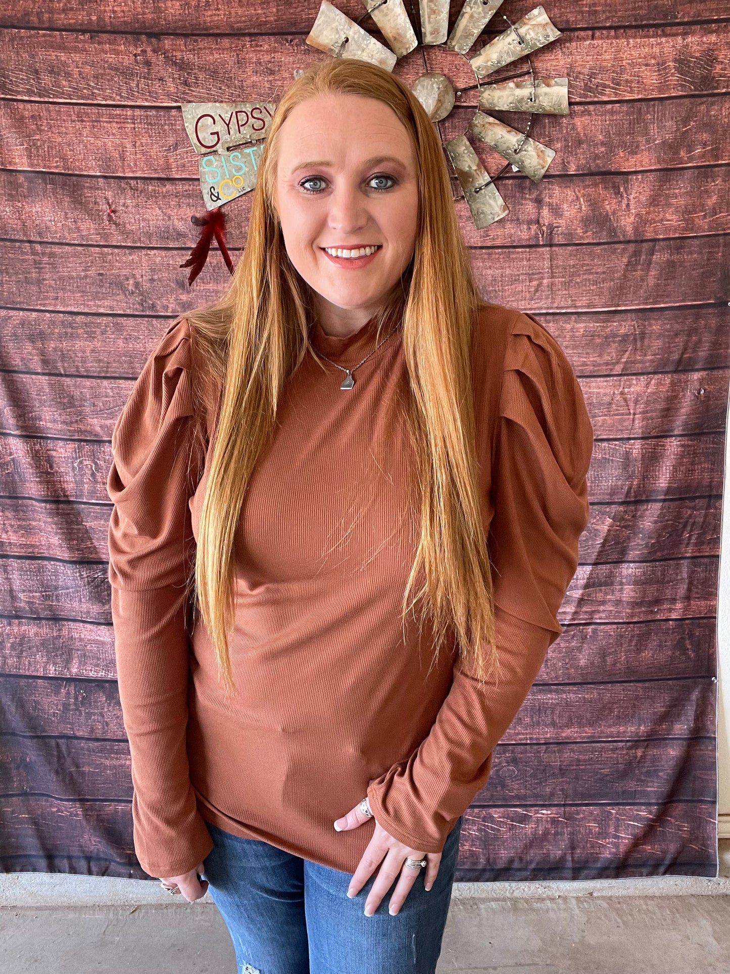 Model wearing brown top with mock neck and puffy sleeves in size large