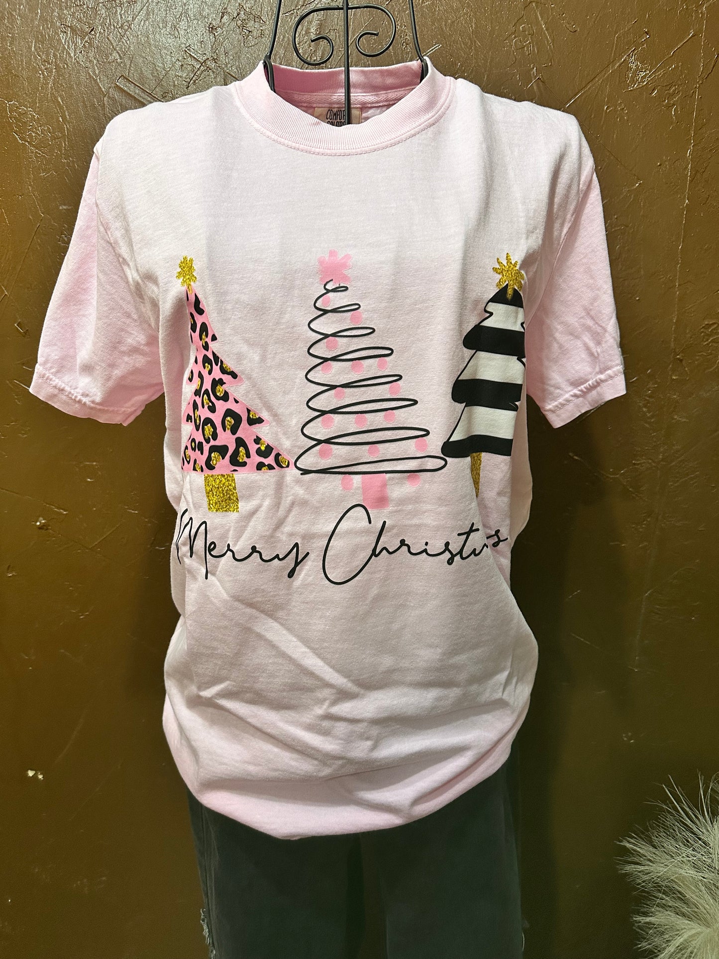 Light pink tee with three Christmas trees with words "Merry Christmas" on a mannequin