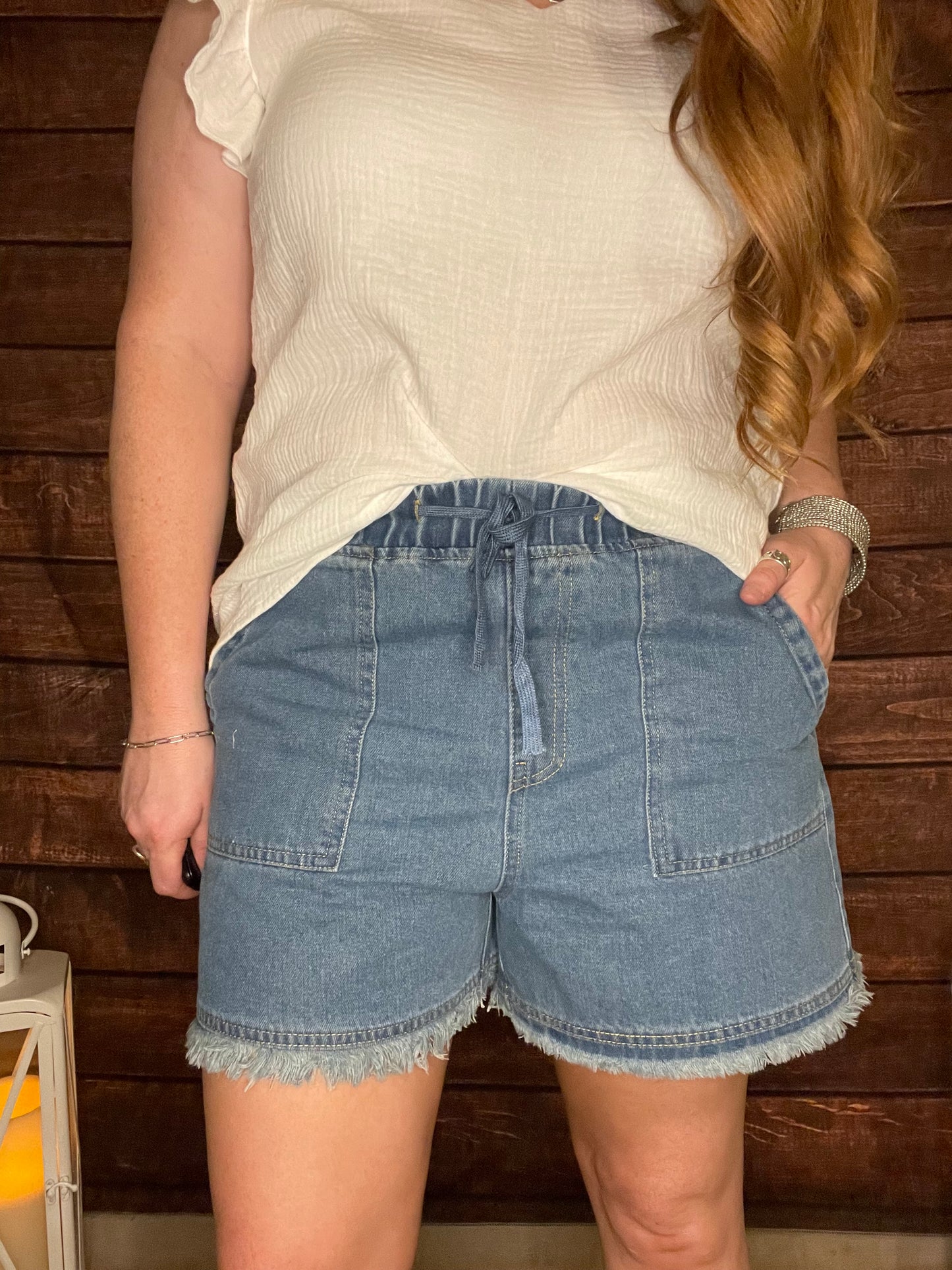Model wearing denim casual shorts with elastic drawstring waist, and Frey hem