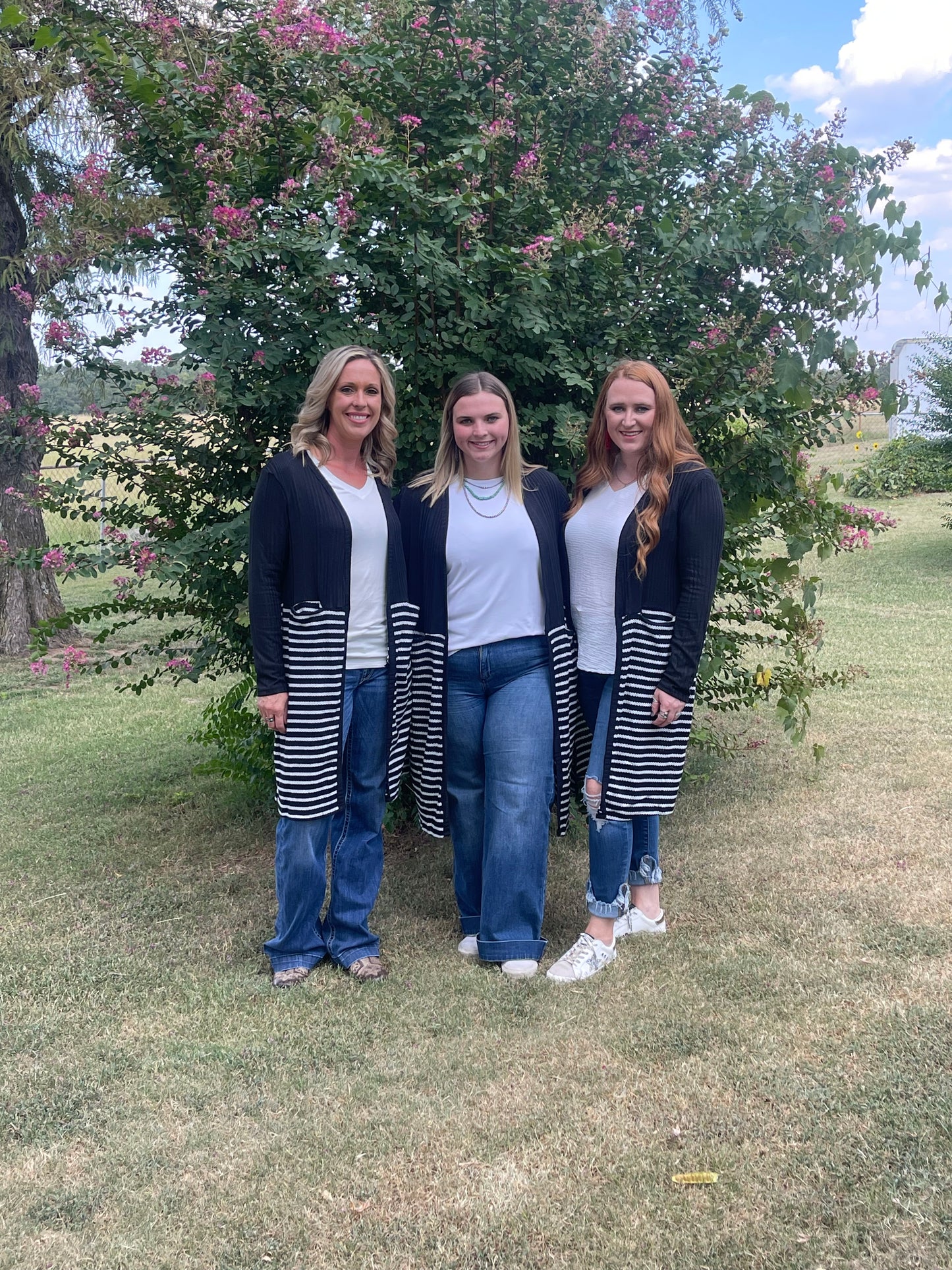 Three women all wearing long black and white striped duster in different sizes