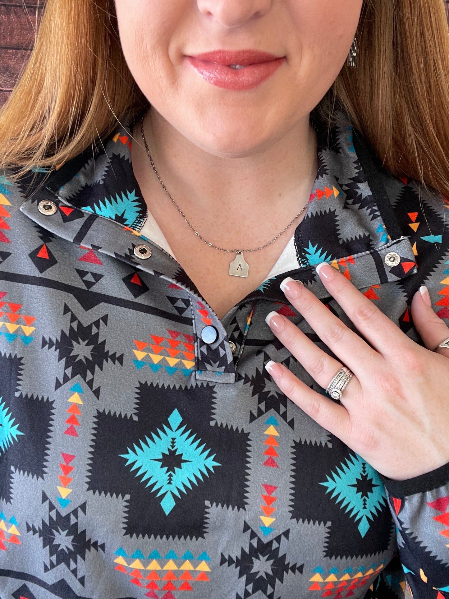 Model wearing Aztec printed light gray pullover showing close up of quarter button neck 