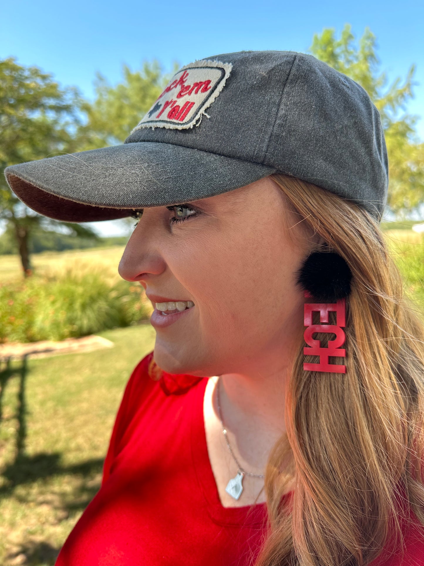 Woman wearing red earrings that say TECH with black puff 