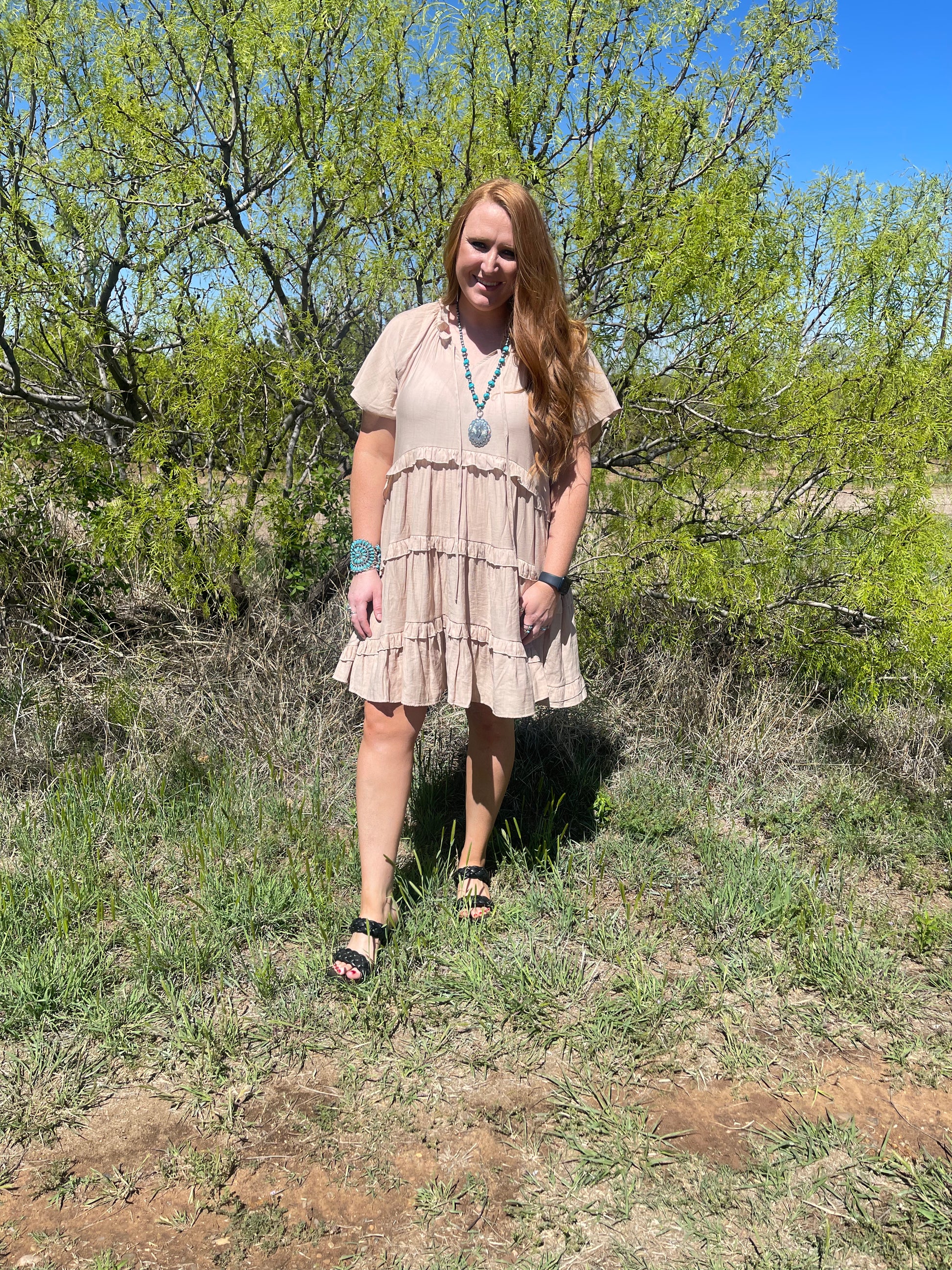 Model wearing ruffle tiered khaki dress with black heeled sandals 