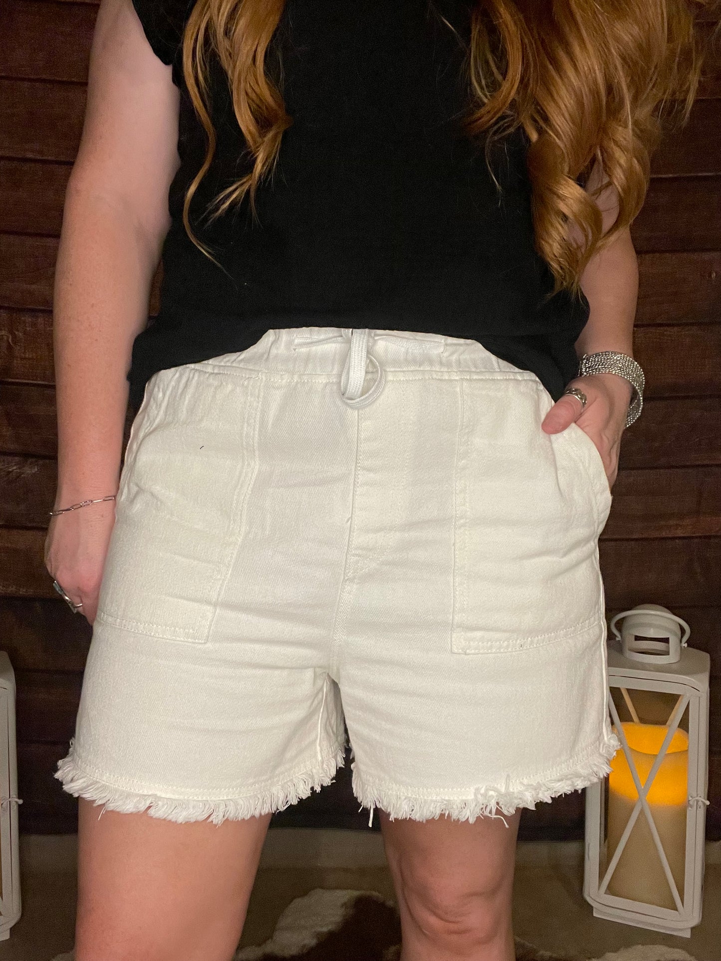 Model wearing white casual shorts with elastic drawstring waist, and Frey hem