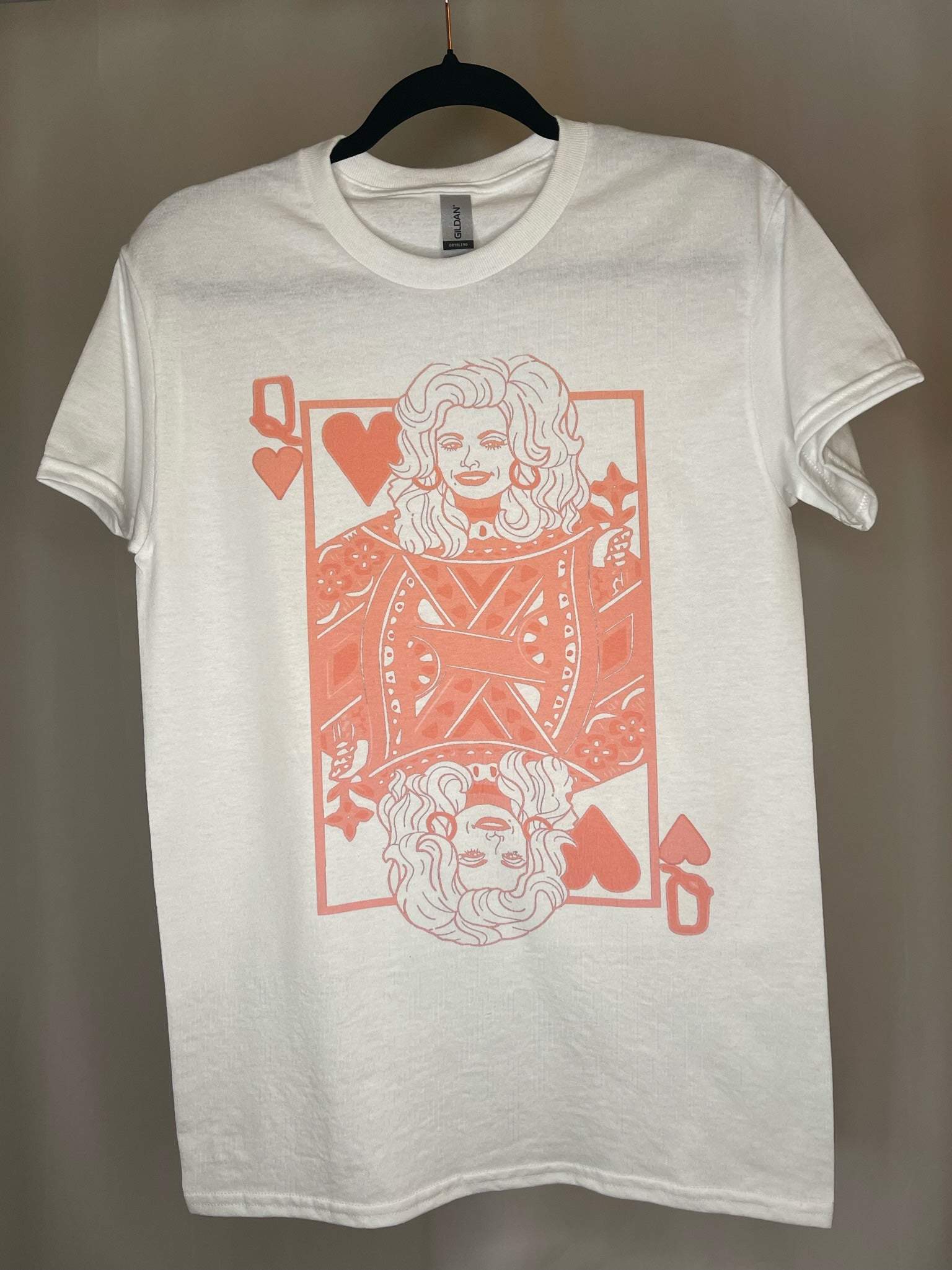 White t-shirt with queen of hearts playing card graphic in pink with Dolly Parton as the queen