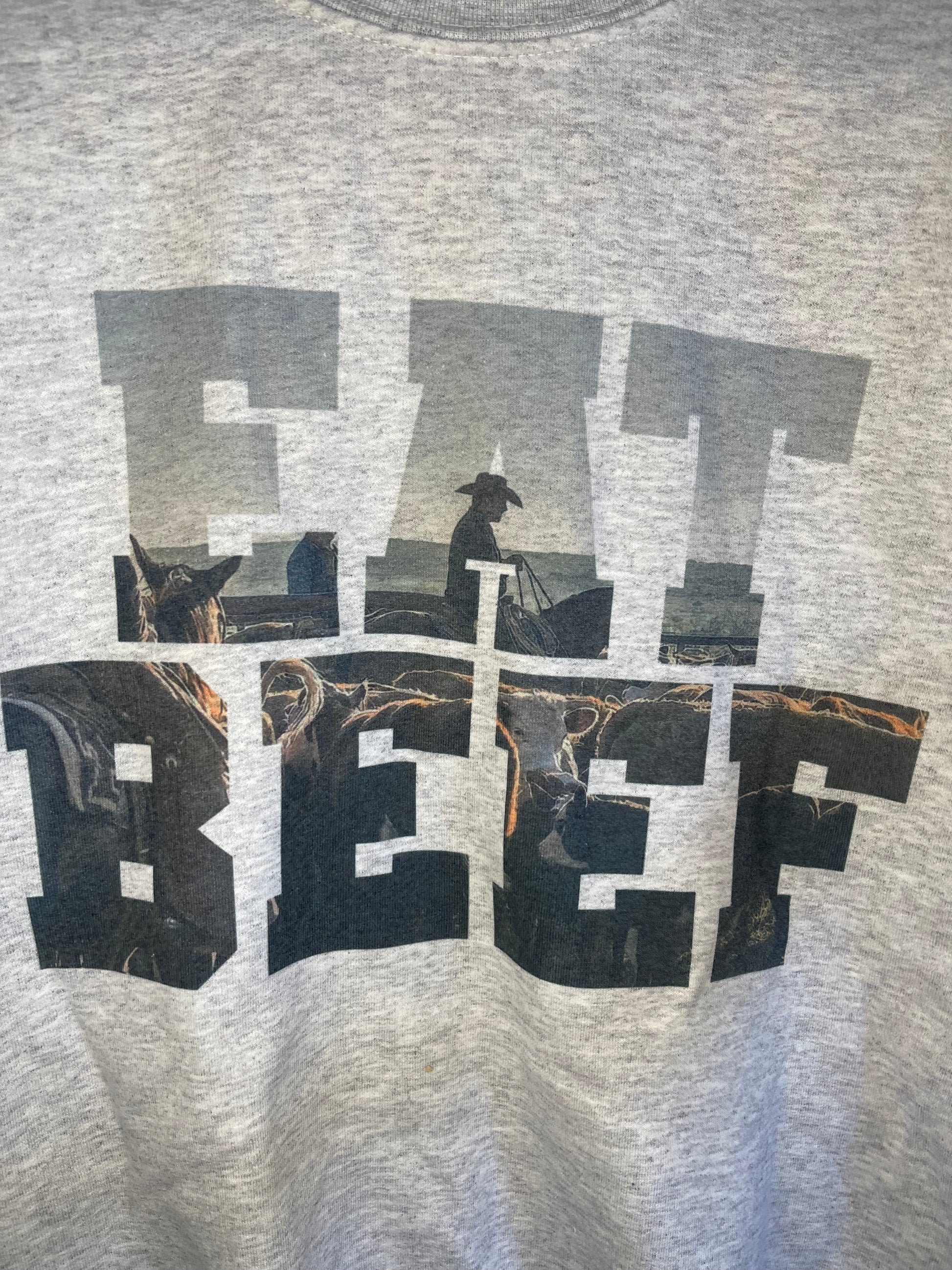 Close up of Light grey sweat shirt that says Eat Beef with a cowboy and cow in the letters