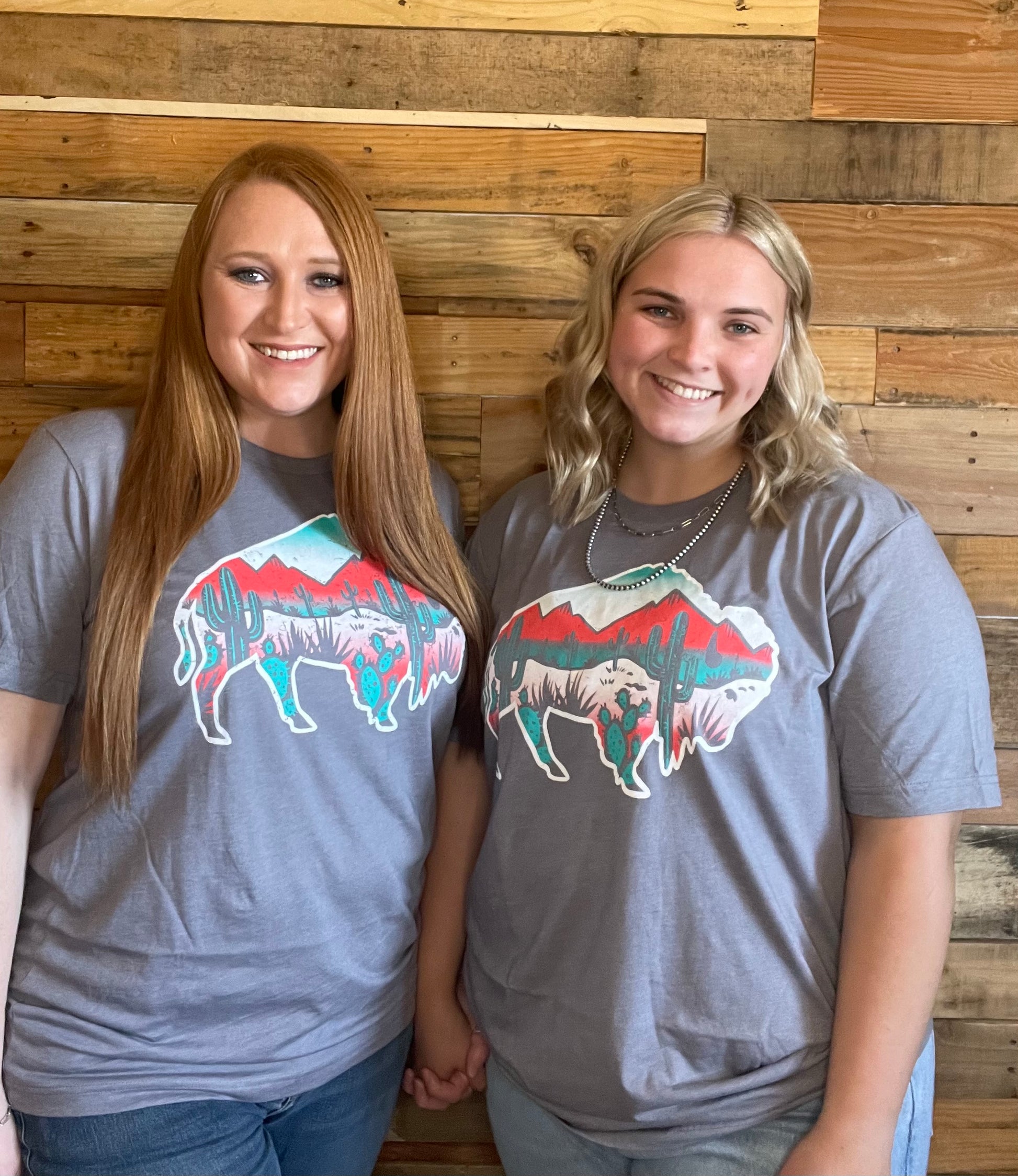 Two Models wearing grey shirt with Buffalo filled with colorful desert scenery 