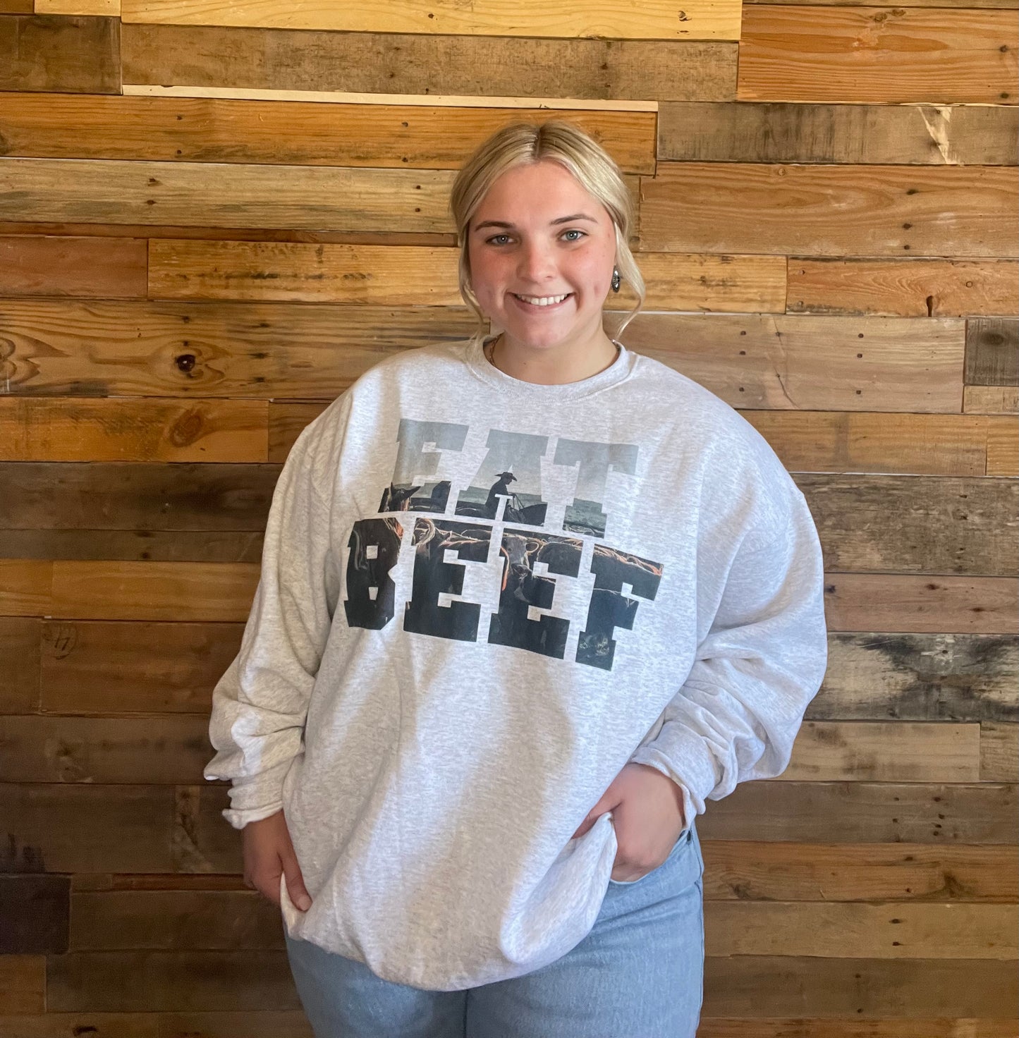 Model wearing Light grey sweat shirt that says Eat Beef with a cowboy and cow in the letters in X-large 